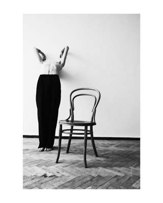 Ilya, photographed by Lilit L Hovhanni: standing beside a bentwood chair, face hidden behind raised arms.