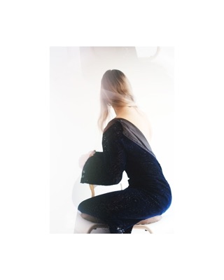 Syuzi, photographed by Lilit L Hovhanni: a woman seen from behind, crouched in a dark dress against white.
