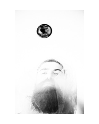 Vengardium leviosa, photographed by Lilit L Hovhanni: a man’s face in bright white light, a dark disc floating above.