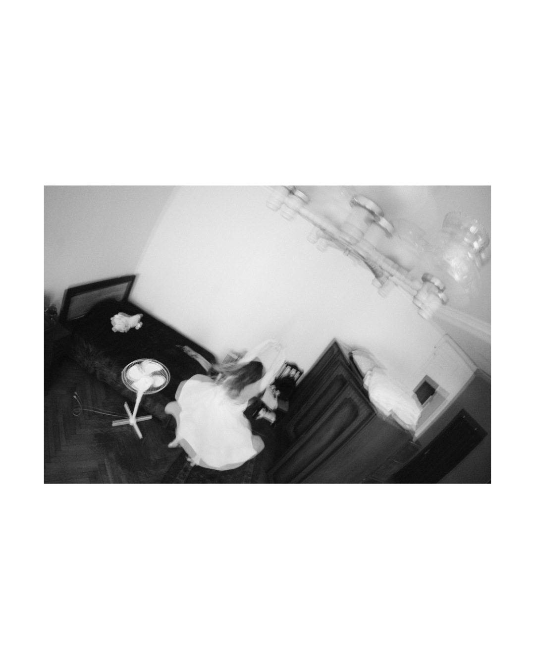 Monochrome view of a woman inside a room with wooden furniture and light walls.