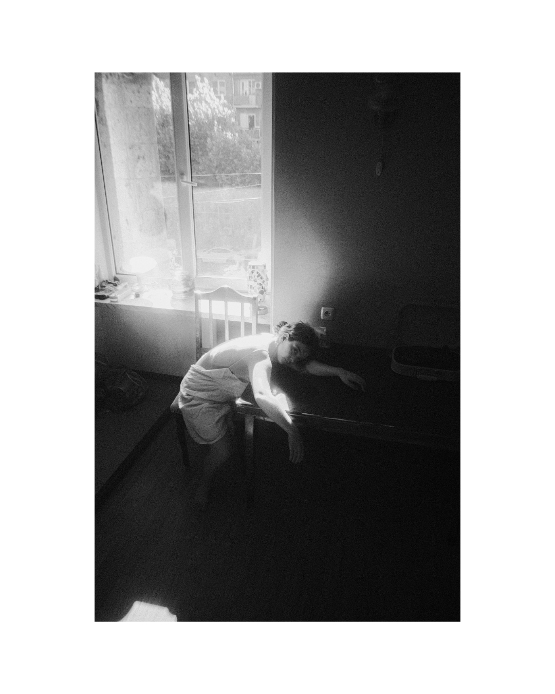 Monochrome view of a woman inside a room with wooden furniture and light walls.