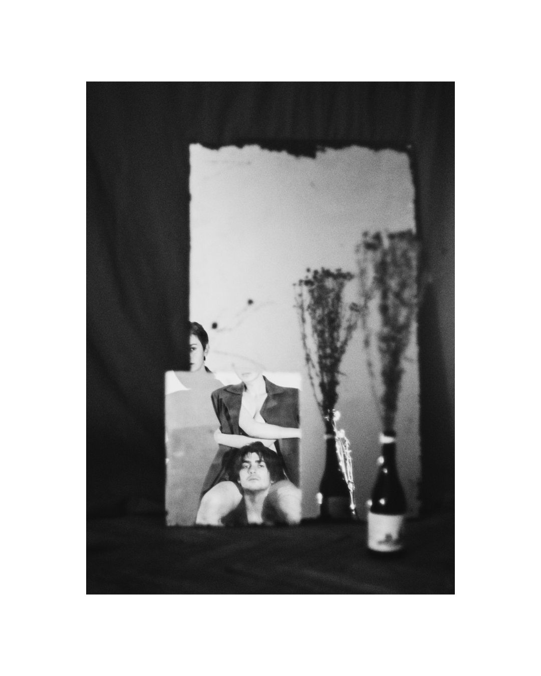 Closely grouped figures in a monochrome interior scene, their bodies partly hidden or cut off by the frame.
