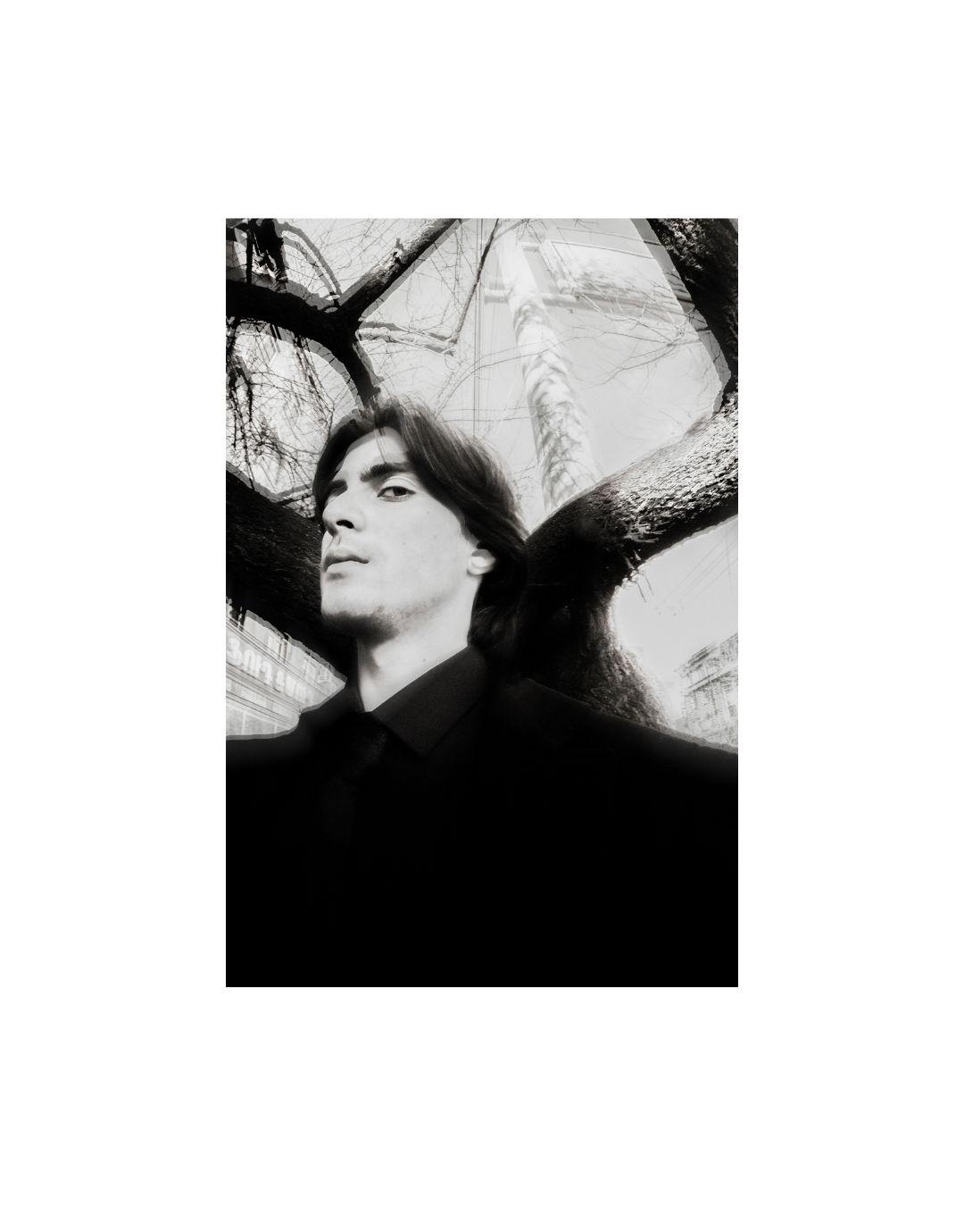 A man's face and dark clothing in an outdoor setting, rendered in black and white.