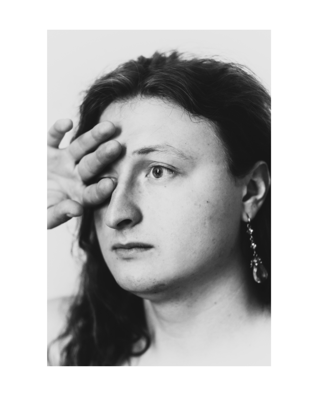 A face and upper body in high-contrast black and white, surrounded by a white border.