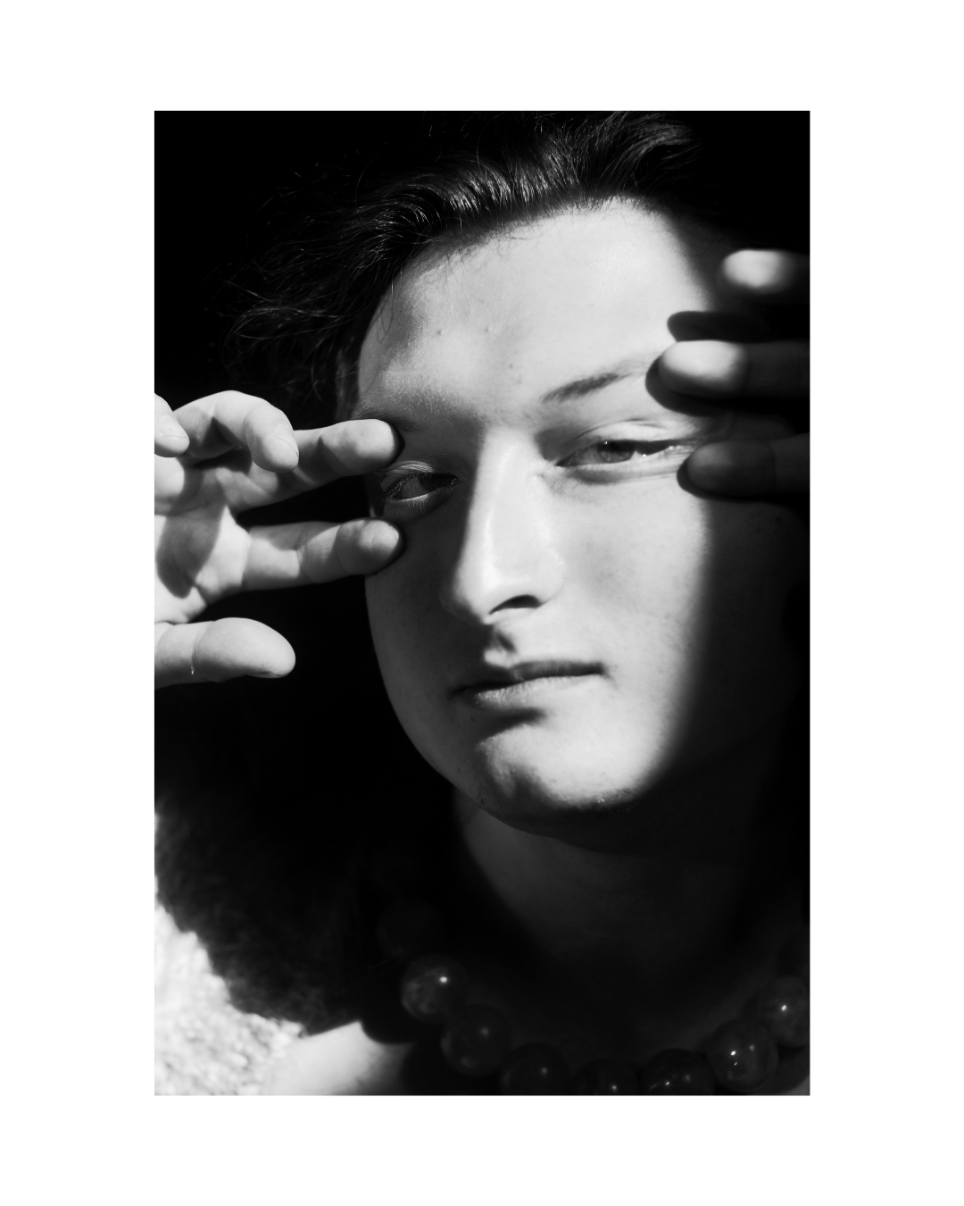 A person fills a vertical black-and-white frame, with bright highlights and deep shadows.
