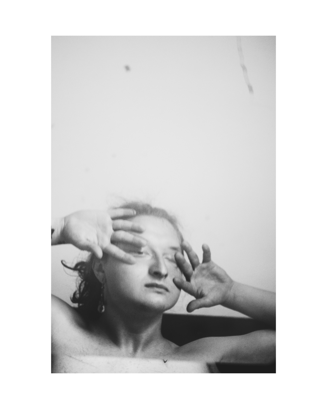 A face and upper body in high-contrast black and white, surrounded by a white border.