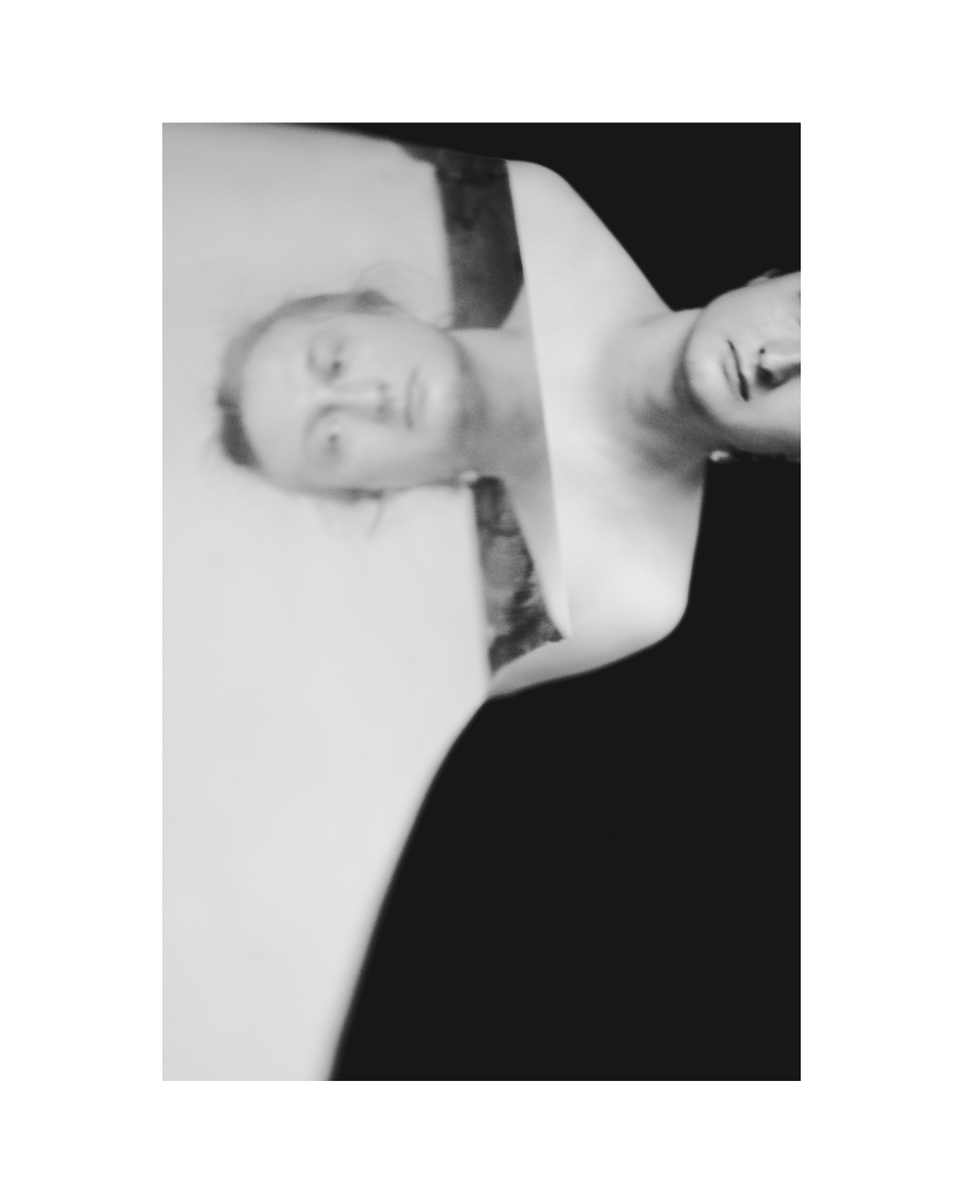 A closely framed face with dark, loose hair and bare skin visible around the neck.