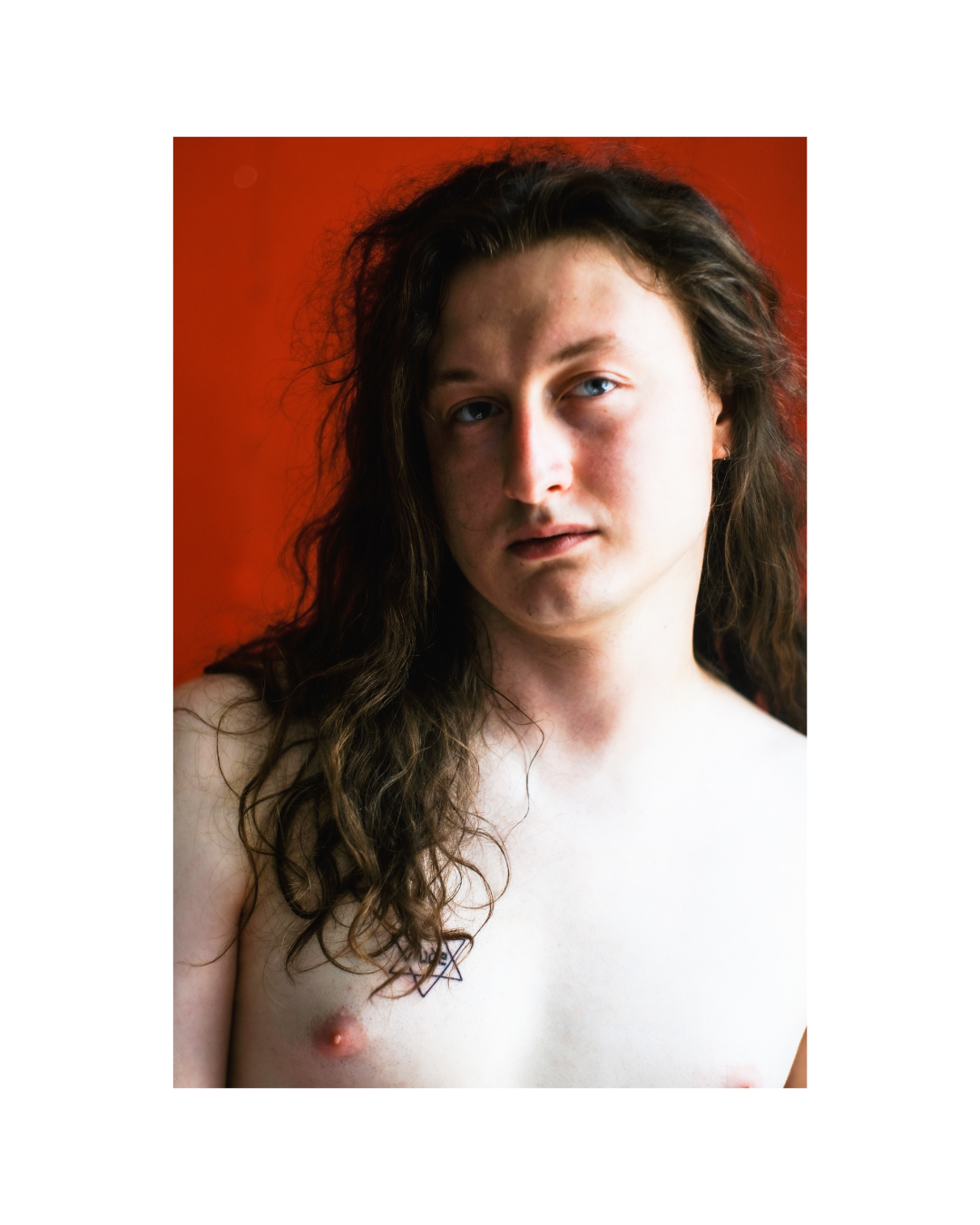 A long-haired person fills a vertical composition set within a wide white border.
