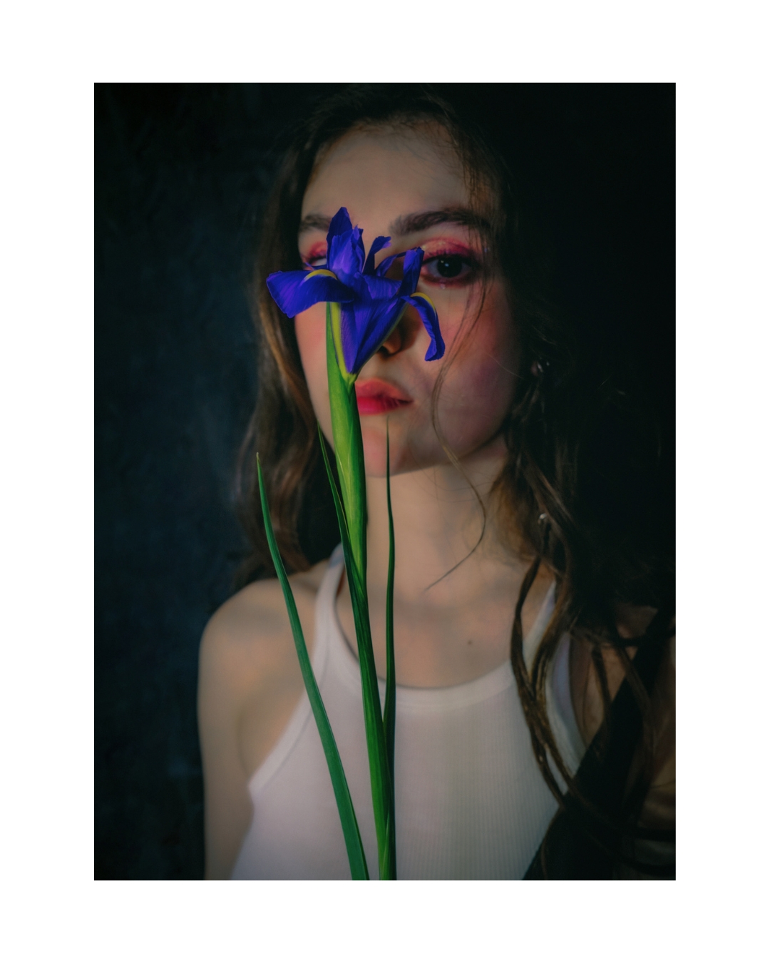 A woman with dark hair looks toward the camera in a tightly cropped vertical portrait.