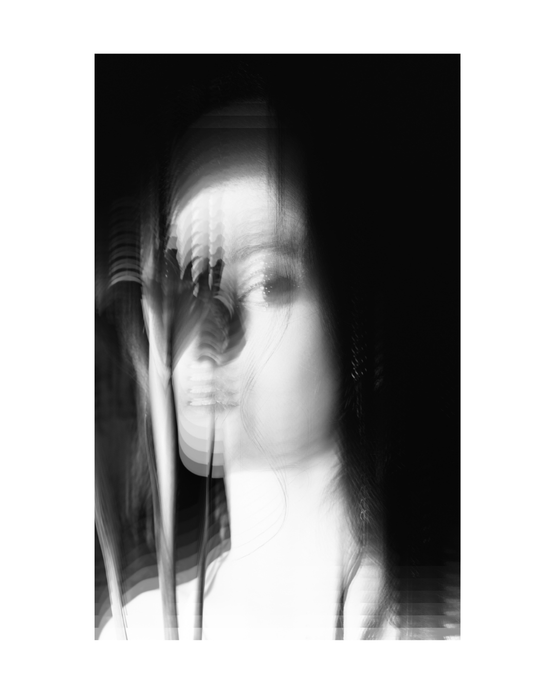 A dark-haired woman faces the camera within a white border, her face and upper body closely framed.