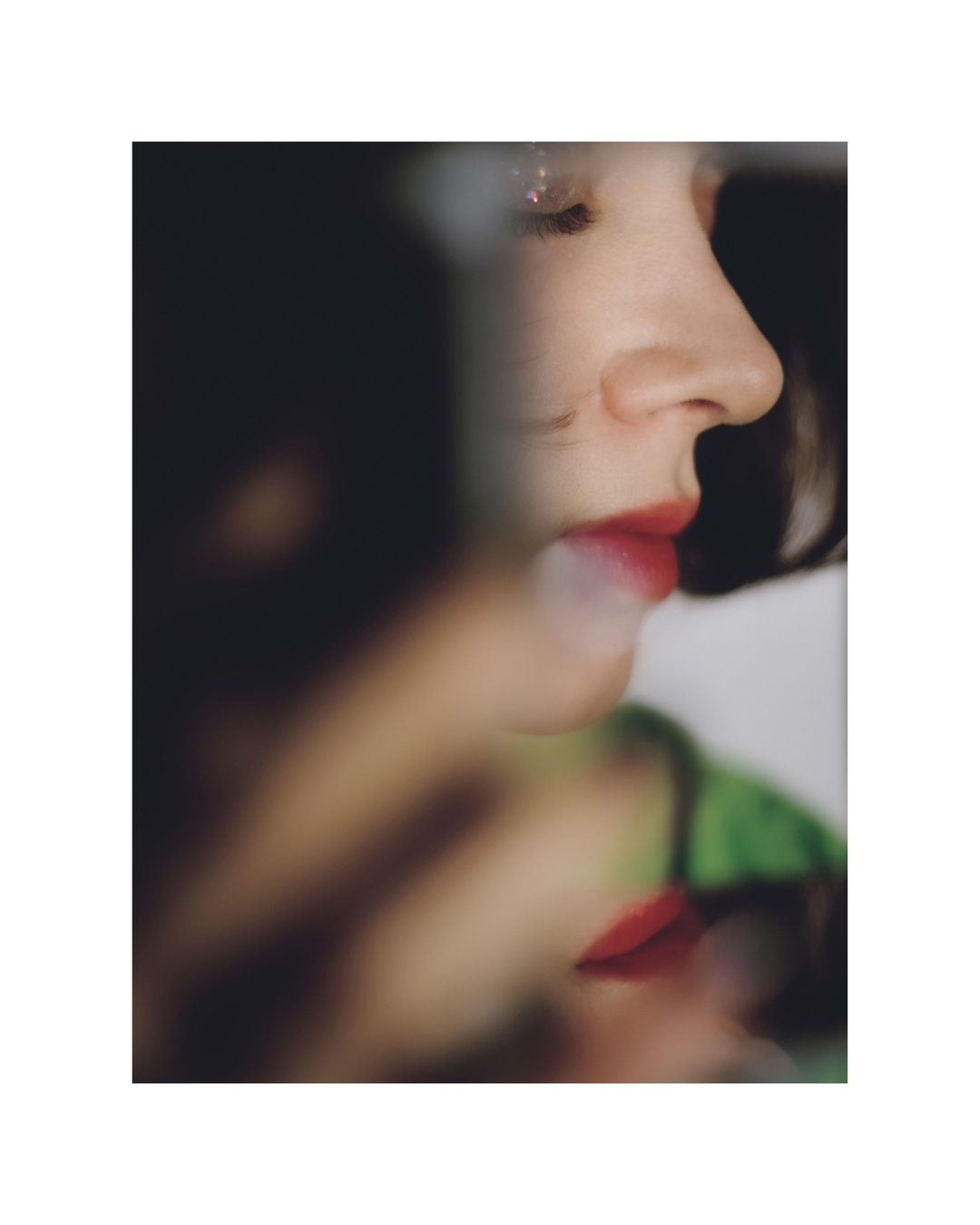 An indoor view of a figure with dark hair, softened edges and areas of deep red.
