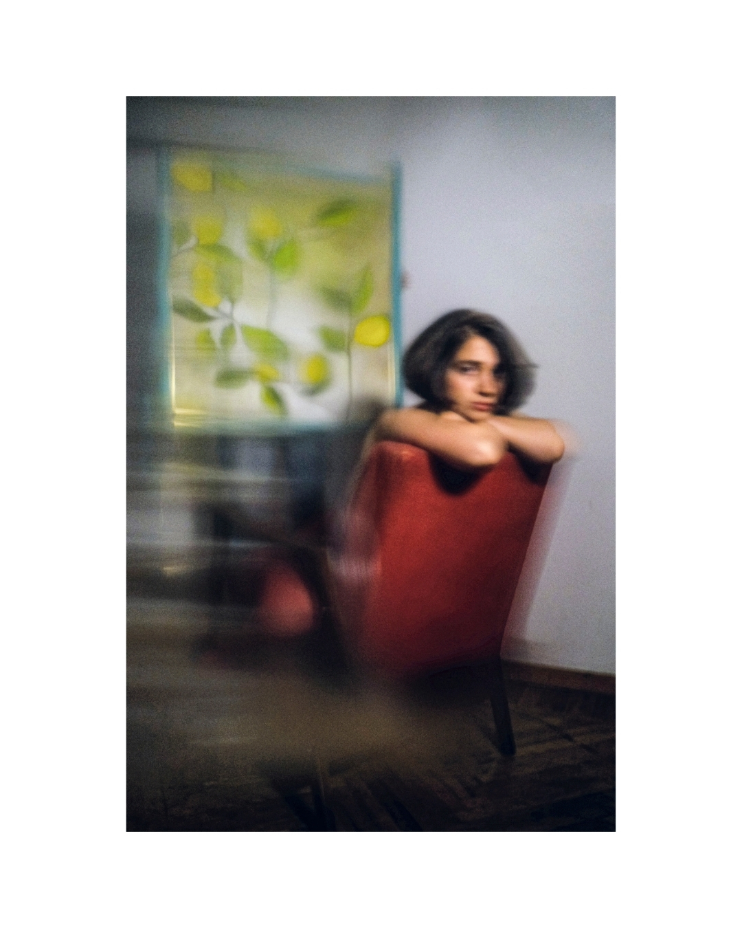 An indoor view of a figure with dark hair, softened edges and areas of deep red.