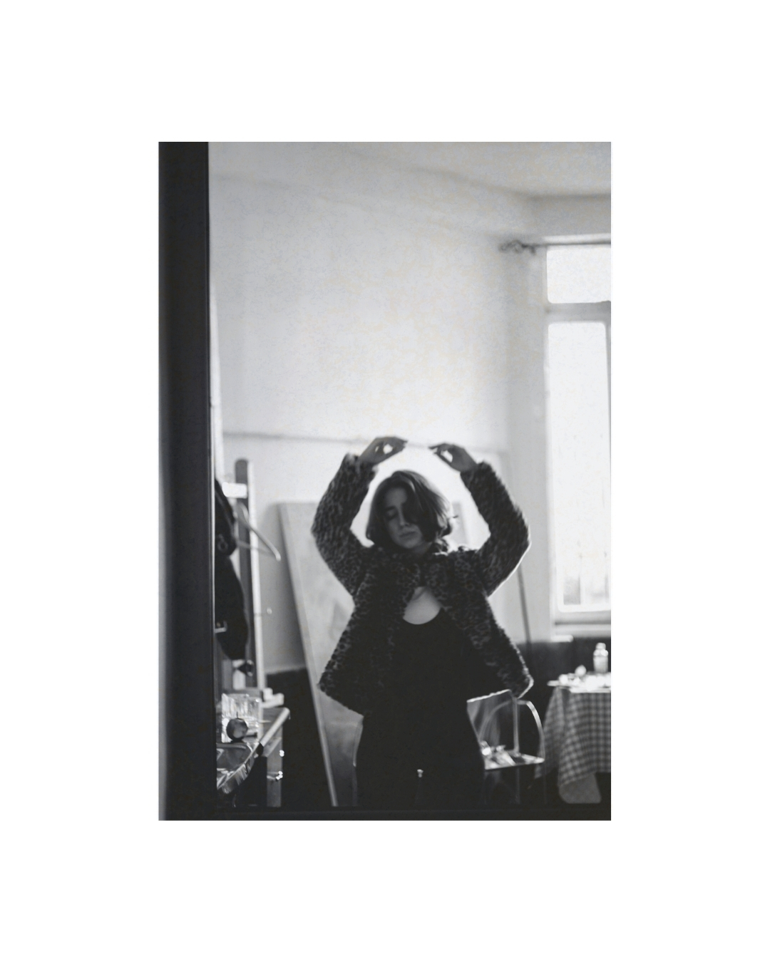A woman indoors in black and white, with dark clothing against lighter walls, by Lilit L Hovhanni.