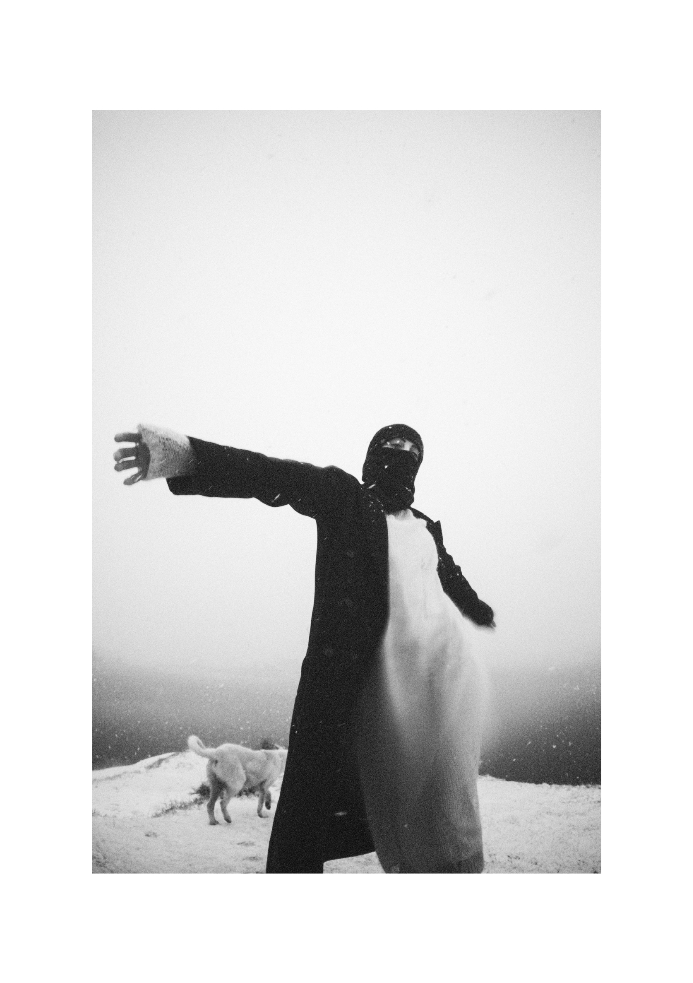 Black-and-white view of a figure in a dark coat, framed with the surrounding snowy ground.