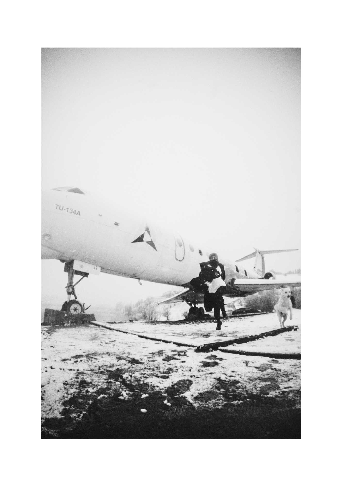 Black-and-white view of a figure in a dark coat, framed with the surrounding snowy ground.