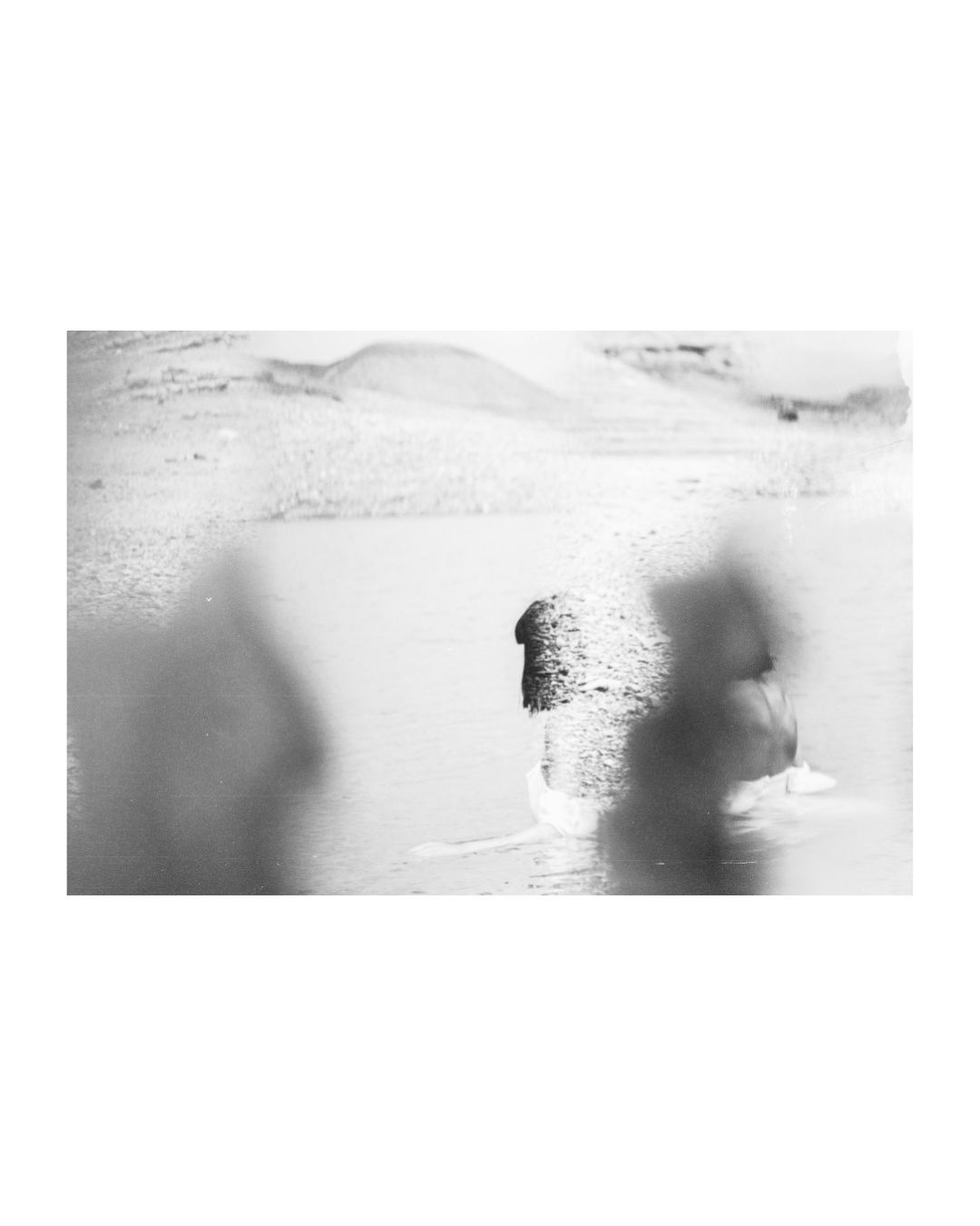 A woman in a rocky waterside setting, in black and white, by Lilit L Hovhanni.