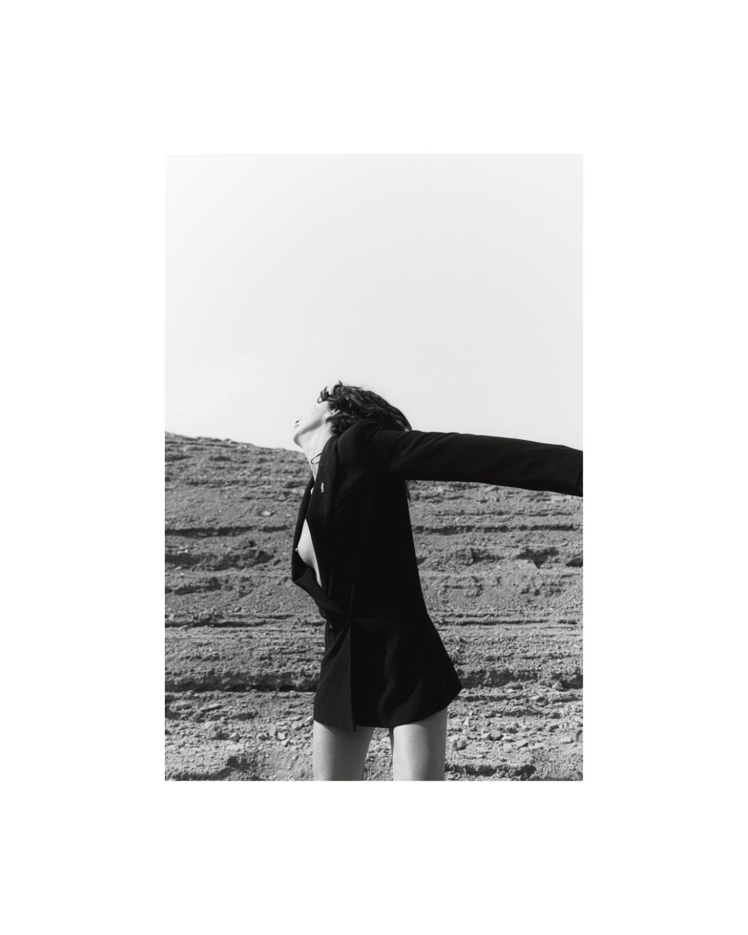 A woman in a rocky waterside setting, in black and white, by Lilit L Hovhanni.