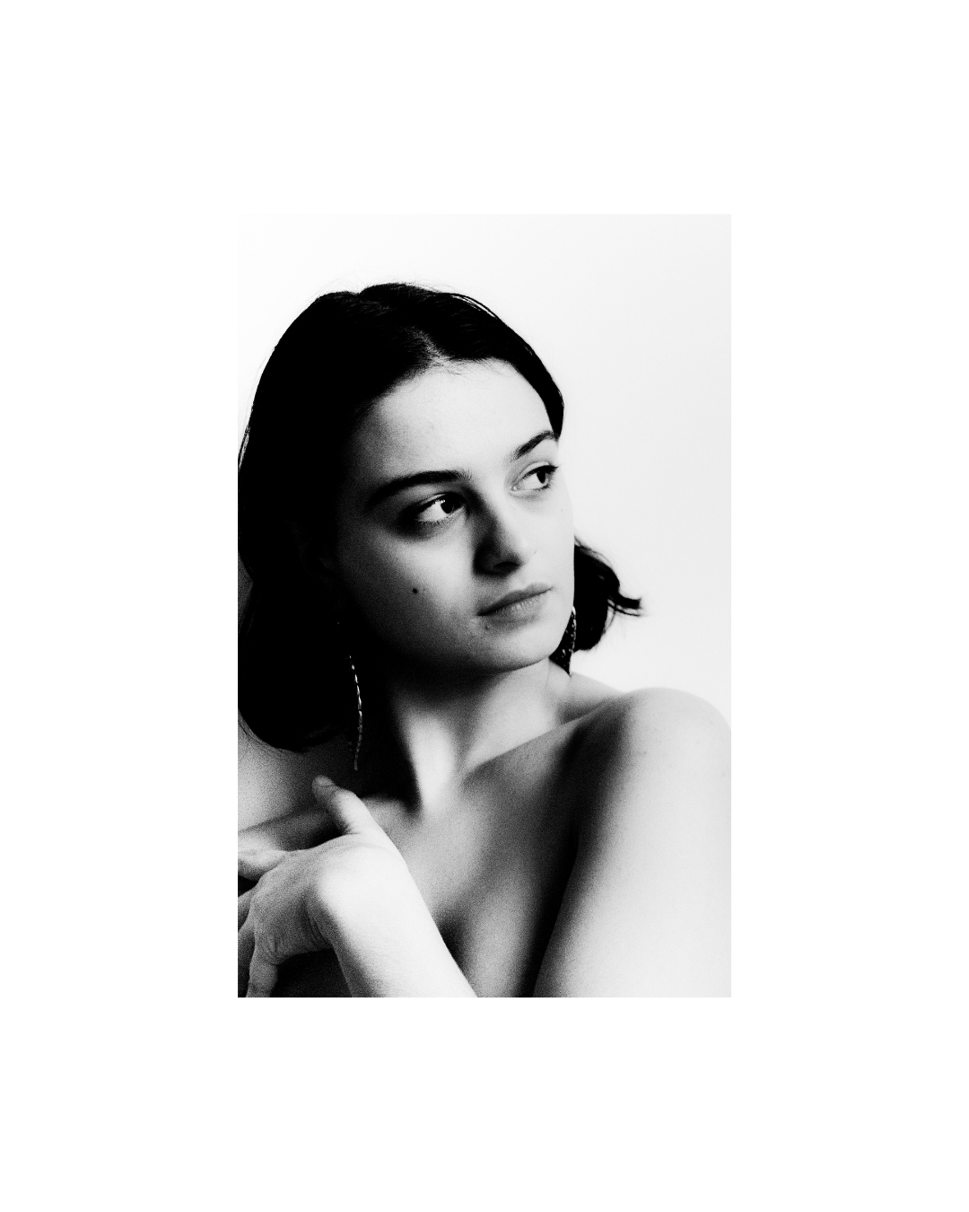 A woman with short dark hair indoors, her face lit against areas of shadow, in black and white.