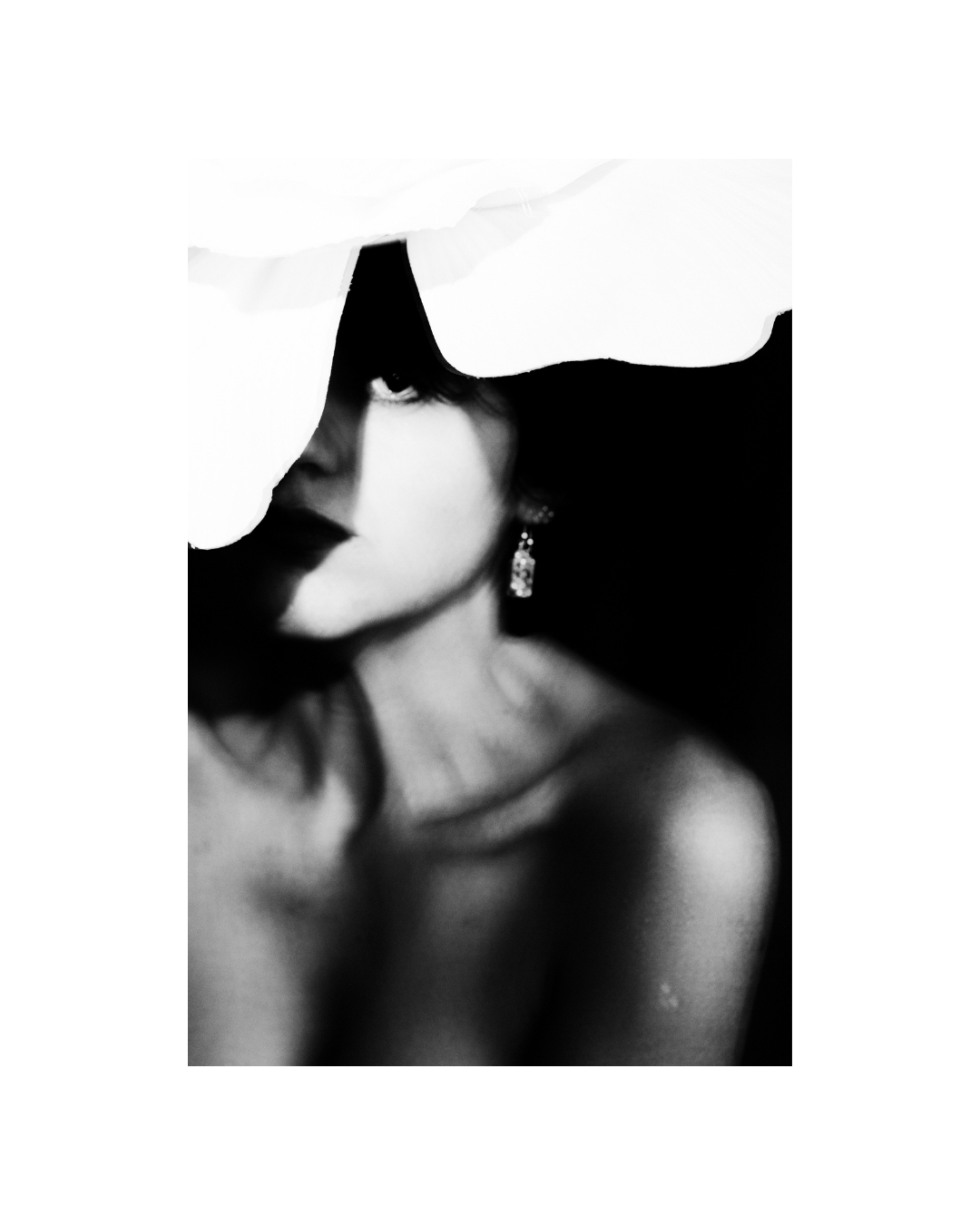 A short-haired woman in black and white, her face partly obscured by overlapping light and dark shapes.