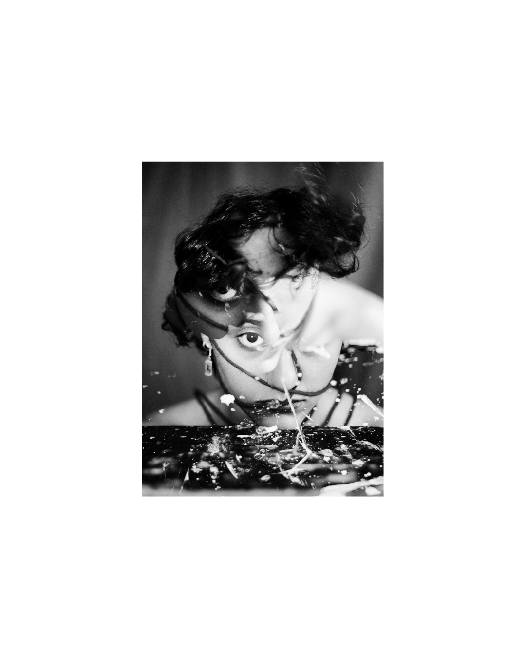 A short-haired woman in black and white, her face partly obscured by overlapping light and dark shapes.