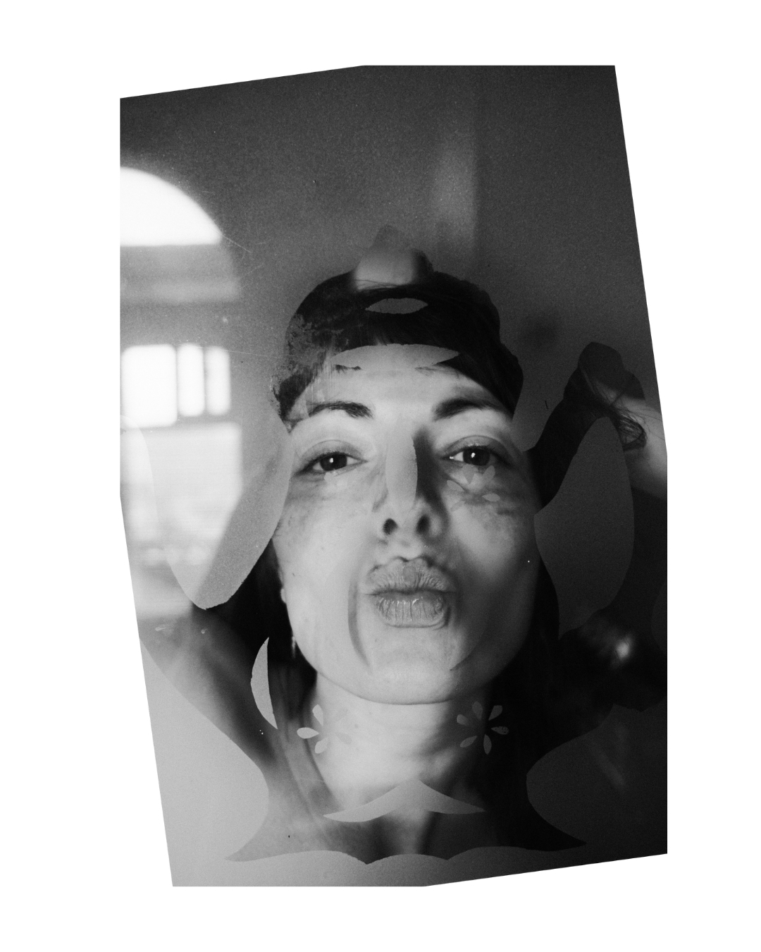 A woman's face overlaps a teapot design on patterned glass in a vertical black-and-white frame.