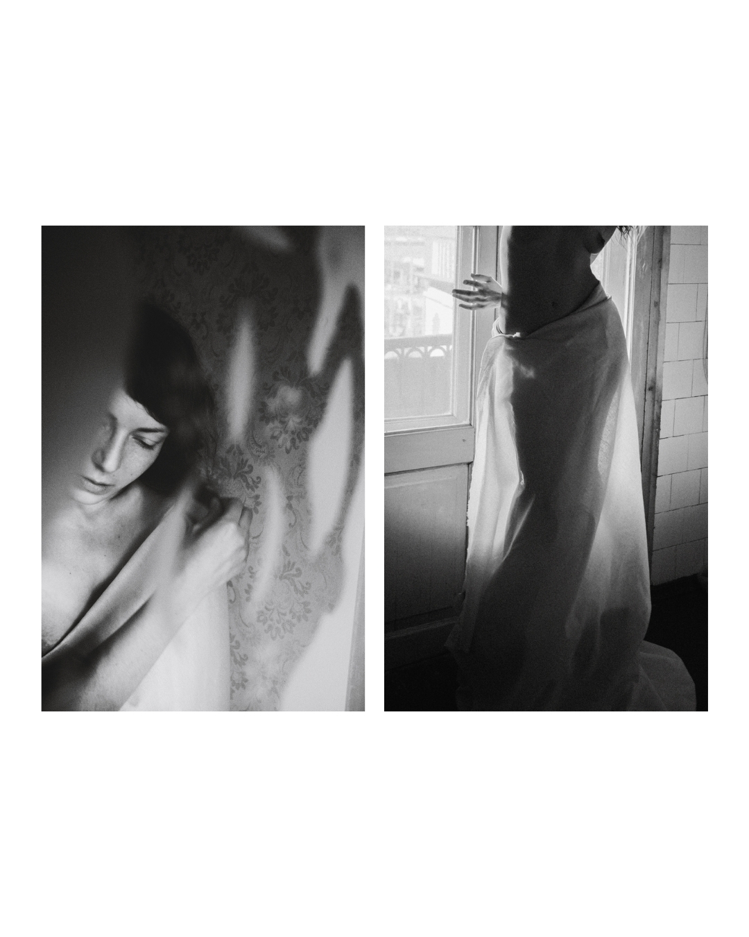 A figure draped in pale cloth poses indoors, with daylight and deep shadows shaping the body in black and white.