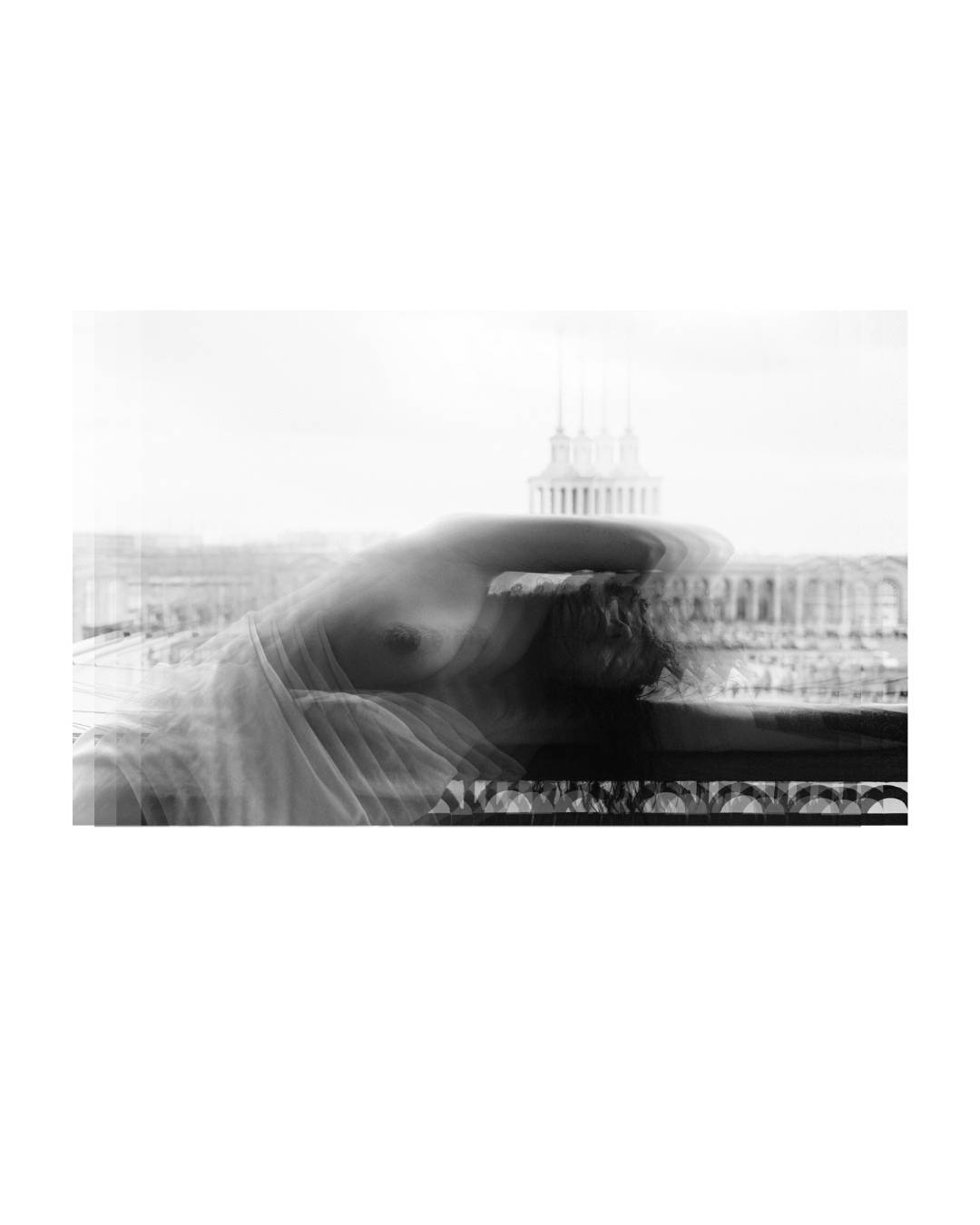 A seated figure framed by architectural surroundings in black and white.