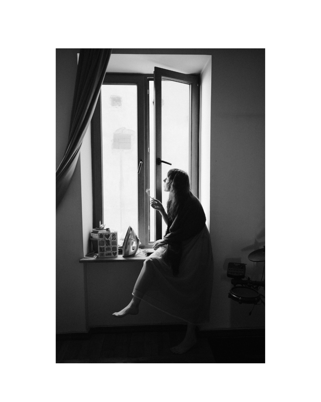 A seated figure shown with part of the surrounding space in monochrome.