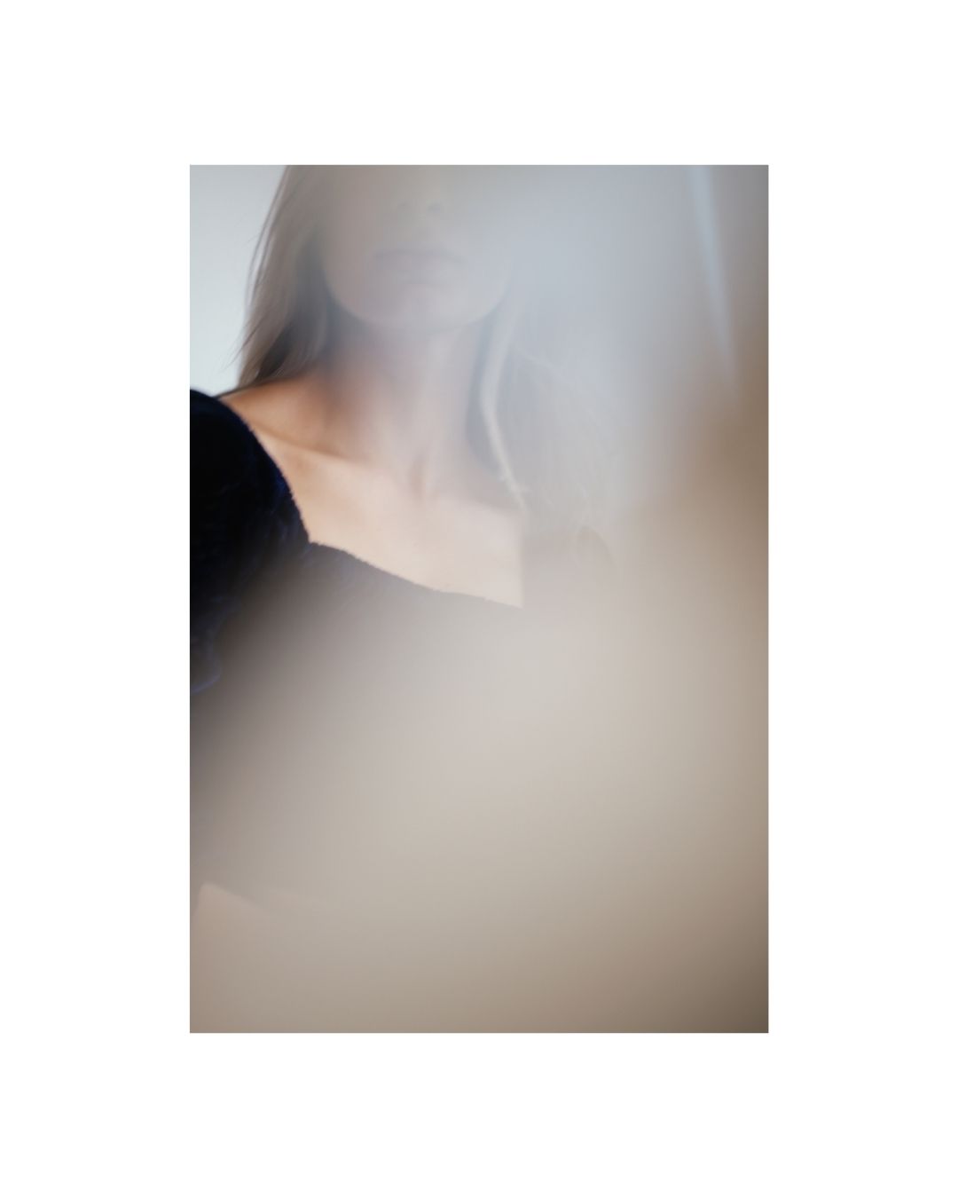 Vertical colour view of a woman in dark clothing against a light wall.