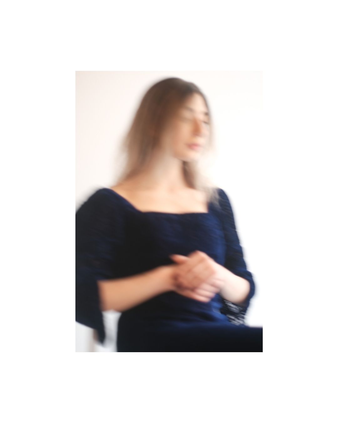 Woman in dark clothing against a pale wall, in colour, by Lilit L Hovhanni.
