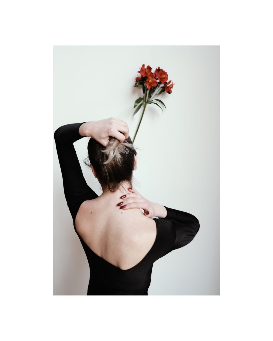 Vertical colour view of a woman in dark clothing against a light wall.