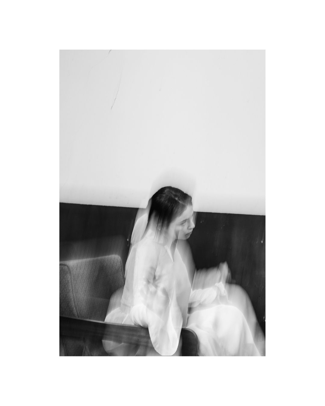 Pale fabric stands out against a dark wall in a black-and-white frame with wide white margins.