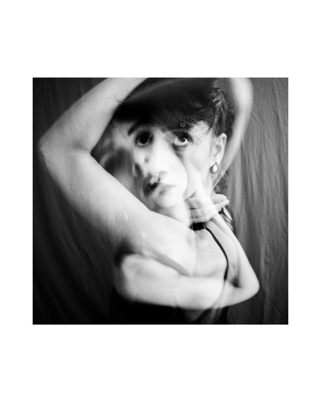 A person fills a vertical frame, with parts of the body cropped and a broad white border around the scene.