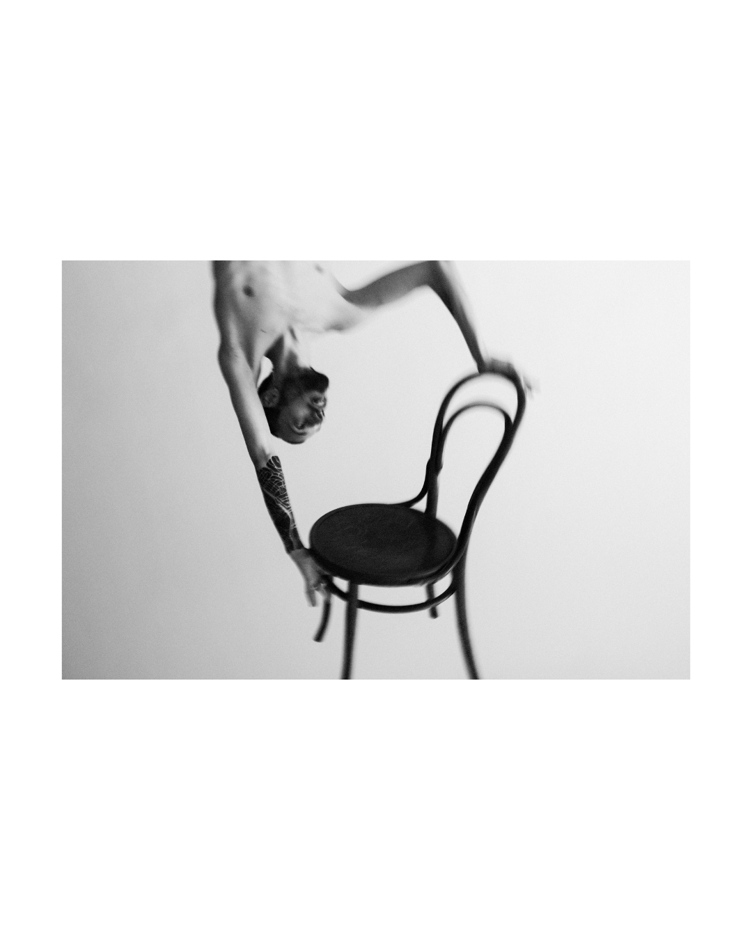 Black-and-white composition pairing facial features with a hand gesture against pale tones.