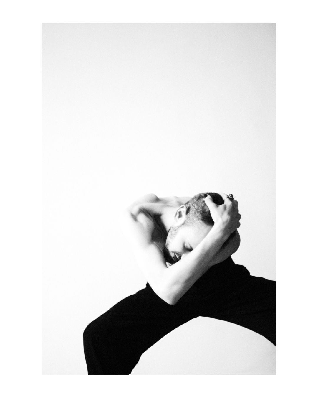 Black-and-white composition pairing facial features with a hand gesture against pale tones.
