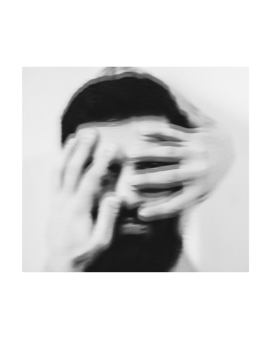 A figure's facial details are obscured against a light background in a vertically framed monochrome view.